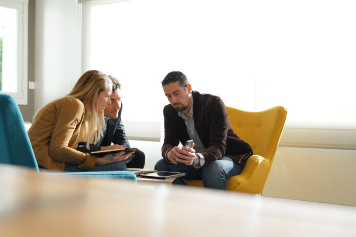 Media sales rep showing clients a digital advertising example on his phone.